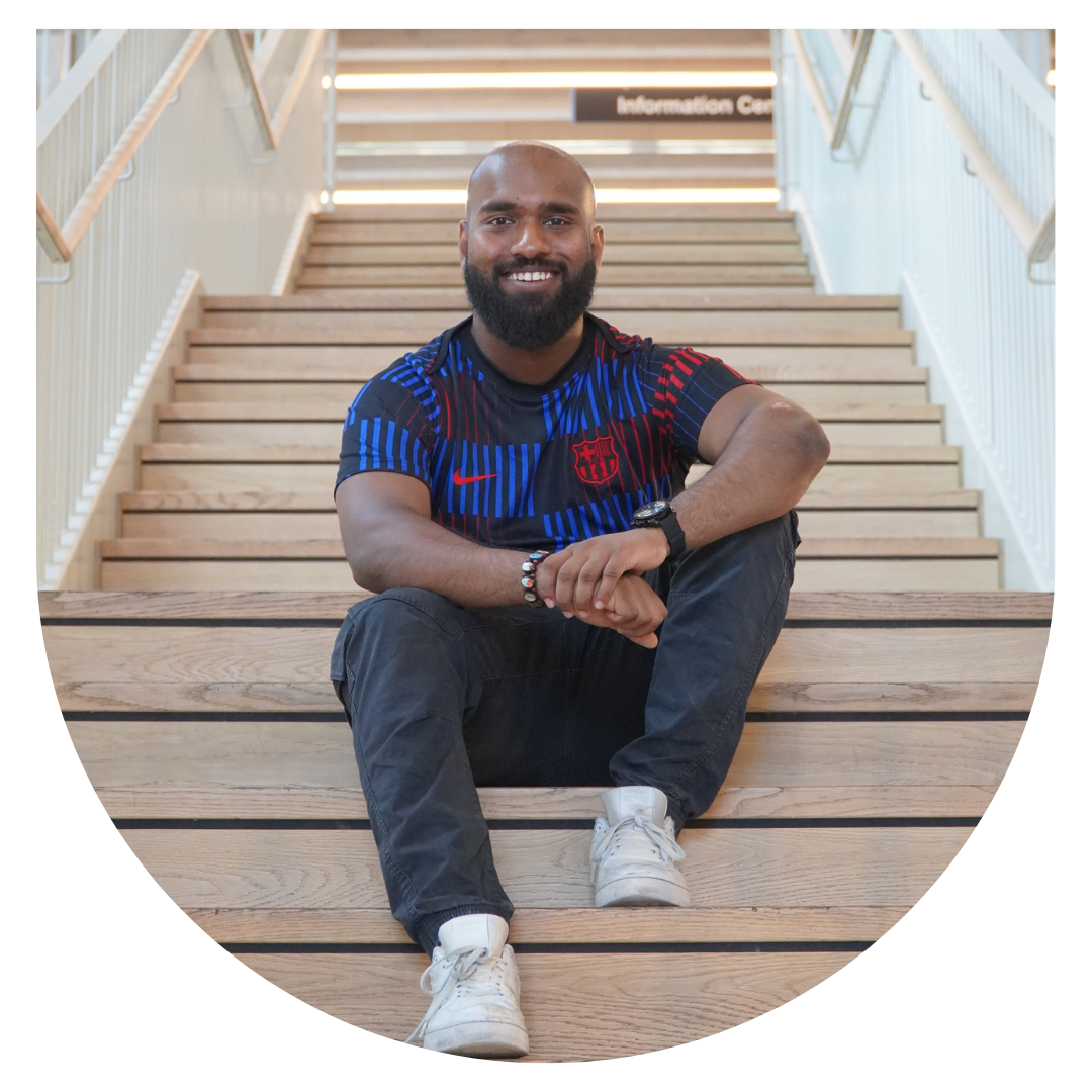 A person sitting on the stairs, wearing black trousers and a football jersey