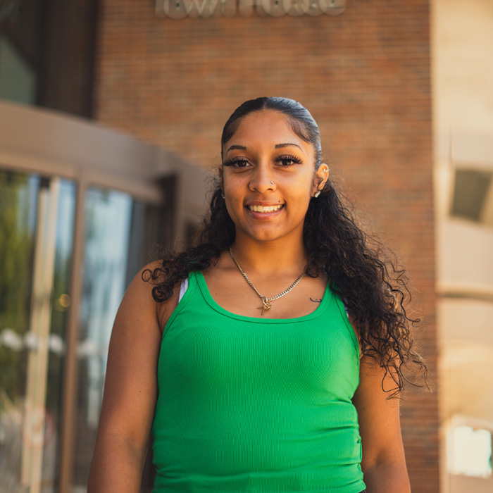 Person with shoulder length black hair wearing a green top
