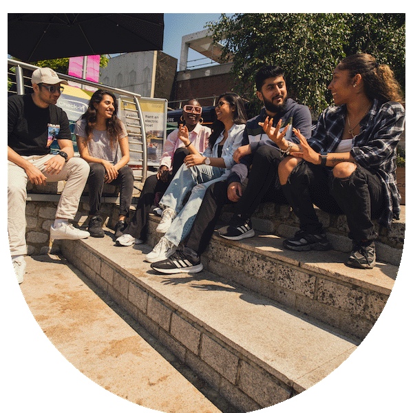 Group of students sat on a step outside a university building