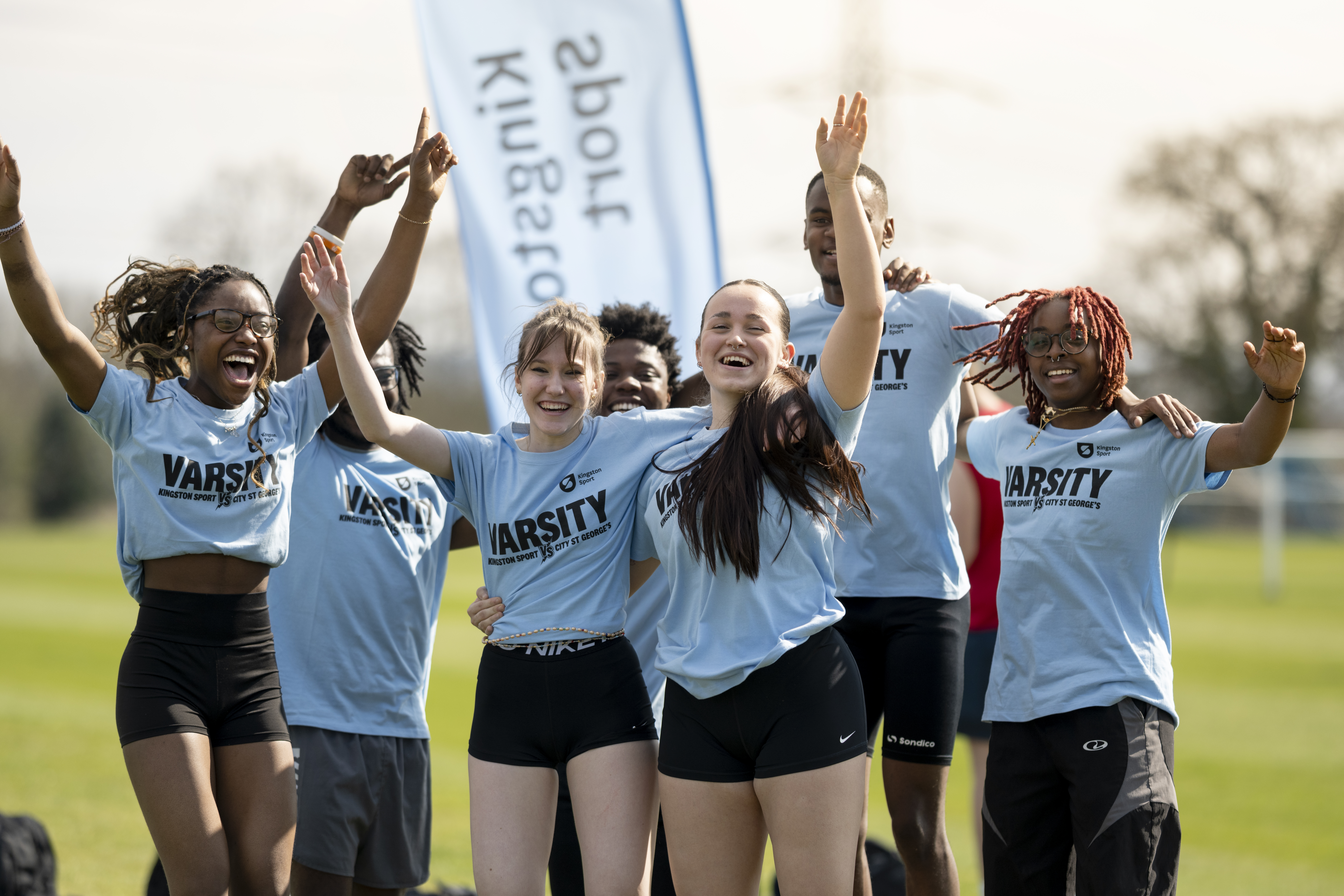 a group image of students jumping out of joy wearing Varsity T-shirts in sky blue colour
