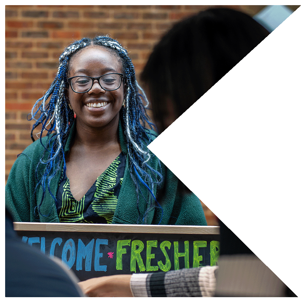 Black person with multicoloured braids wearing glasses and a green top