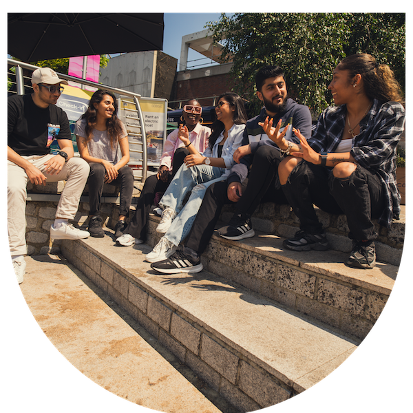 Group of students sat on steps outside on a sunny day